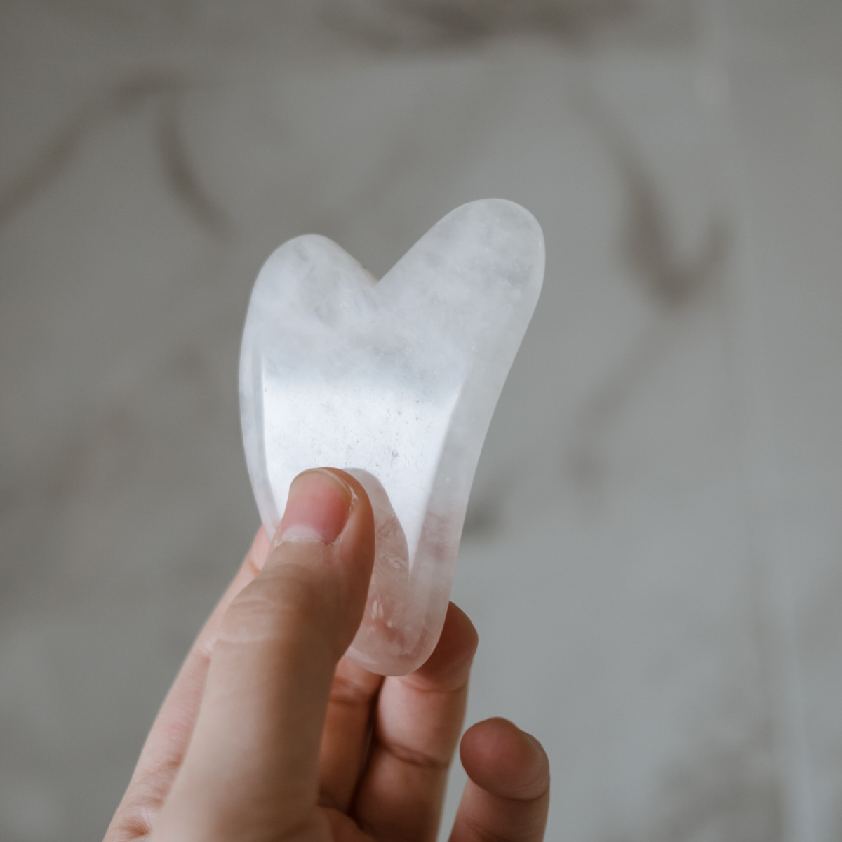 Weisser Gua Sha in Hand gehalten, Badezimmer.