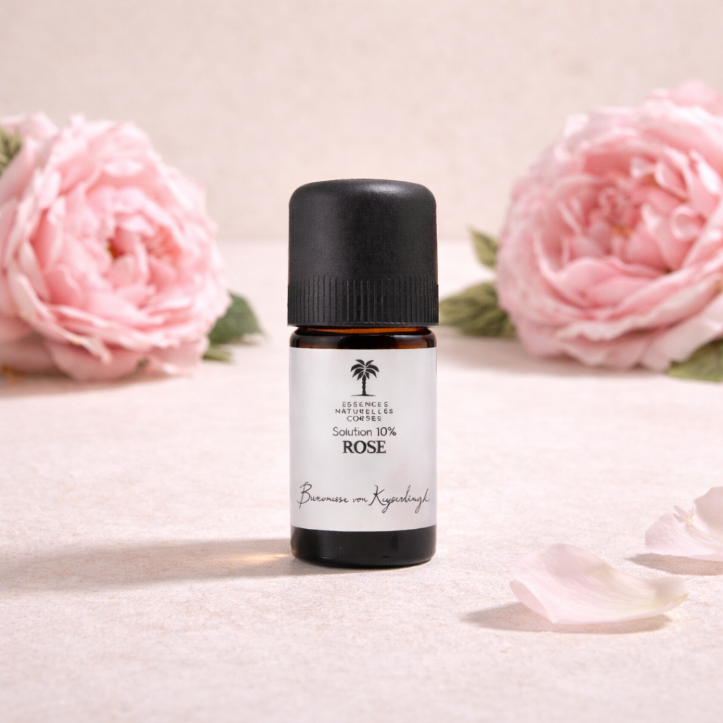 Flasche Bio Blütenextrakt Öl Rose  auf beigeem, cleanem Studio-Hintergrund, mit Infusionszutaten passend zum Öl im Hintergrund. 100 % naturrein, biologisch, pflanzlich und vegan, aus biodynamischem Anbau und Handernte.