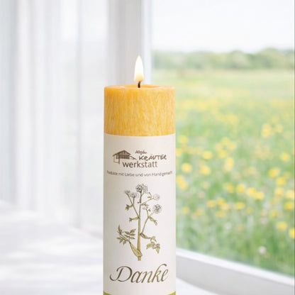 Heilkräuterkerze Danke aus dem Allgäu an Fenster in Close up Baumwolldocht-Flamme und Label.
