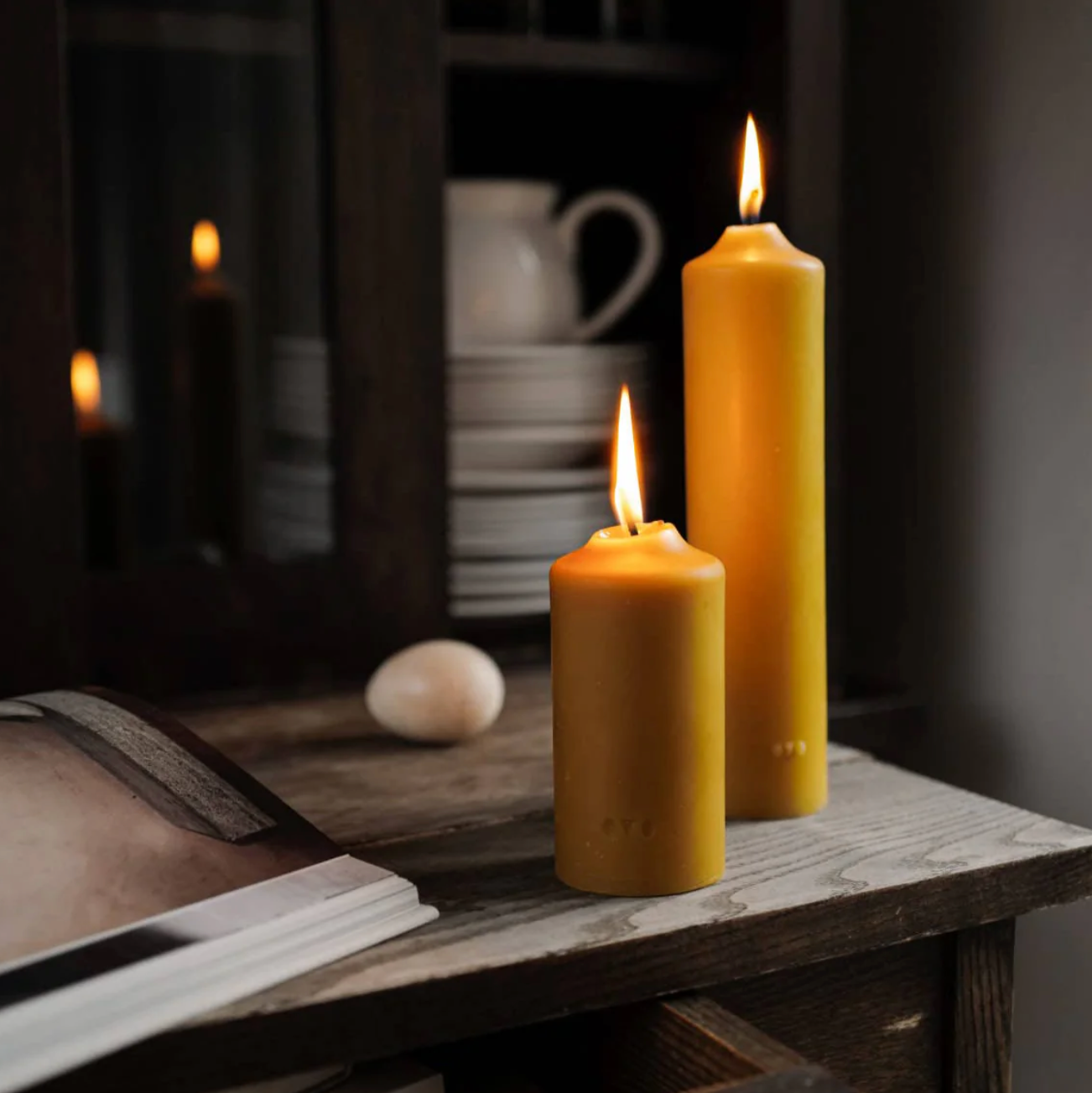Angezuendete Säulen-Bienenwachskerze klein und mittel mit warmem goldgelbem Licht und natürlichem Honigduft dekorativ zu Hause.