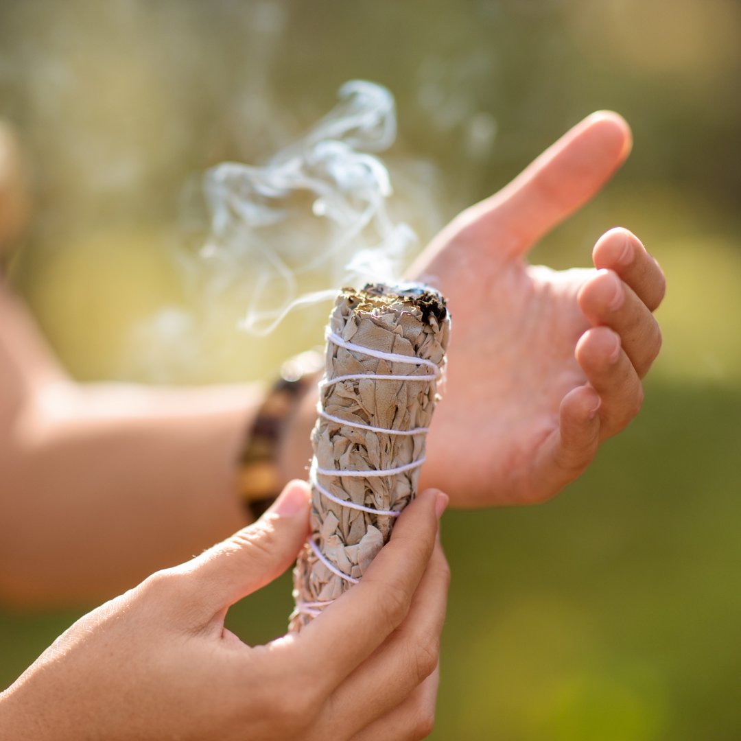 Angezündetes Bündel weißer Salbei mit sanft aufsteigendem Rauch für energetische Raumreinigung.